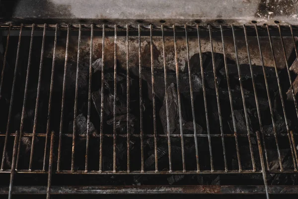 Dark black natural coals under iron bbq grid — Stock Photo