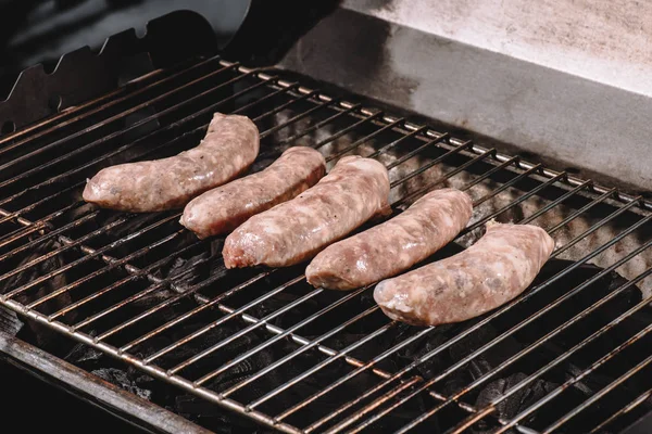 Raw pork sausages cooking on barbecue grill grates — Stock Photo