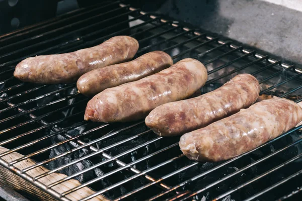 Raw fresh sausages preparing on barbecue grill grate — Stock Photo