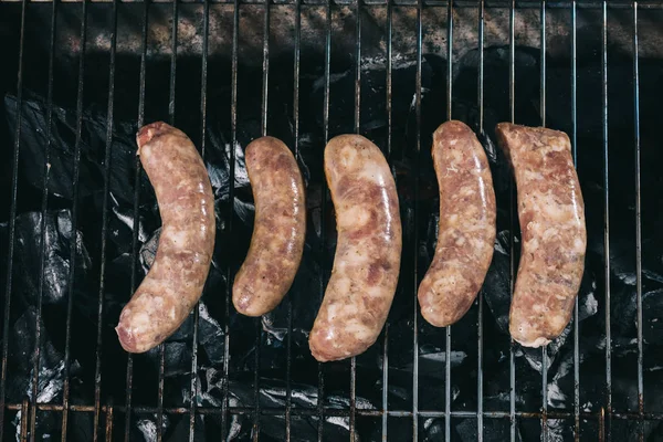 Vista dall'alto di salsicce fresche crude che si preparano su griglia griglia — Foto stock