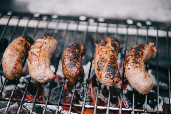 Enfoque selectivo de salchichas deliciosas a la parrilla en la rejilla de barbacoa - foto de stock