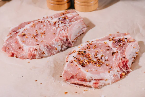 Close up of raw fresh steaks with seasoning on paper — Stock Photo