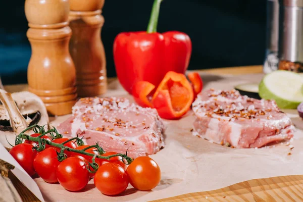 Foco seletivo de bifes crus com tempero e legumes frescos maduros — Fotografia de Stock