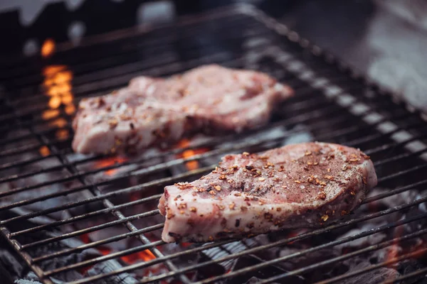 Selective focus of juicy raw steaks grilling on barbecue grid — Stock Photo
