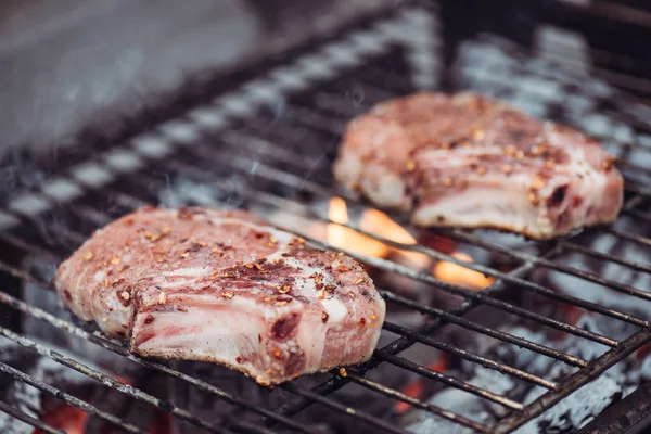 Selective focus of juicy raw steaks grilling on barbecue grid with smoke — Stock Photo
