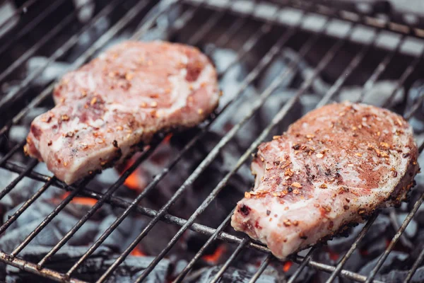 Selective focus of juicy raw steaks grilling on barbecue grid with smoke — Stock Photo