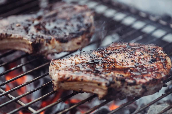 Selective focus of juicy spicy steaks grilling on barbecue grid with smoke — Stock Photo