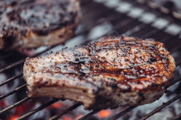 Selective focus of juicy spicy steak grilling on barbecue grid with smoke — Stock Photo