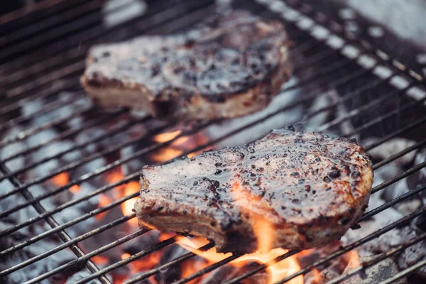 Foyer sélectif de steaks juteux et savoureux grillades sur grille de barbecue avec fumée — Photo de stock