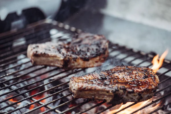 Selective focus of juicy tasty steaks grilling on barbecue grid with smoke — Stock Photo