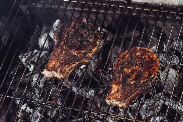Juicy steaks with crust grilling on hot coals with smoke — Stock Photo