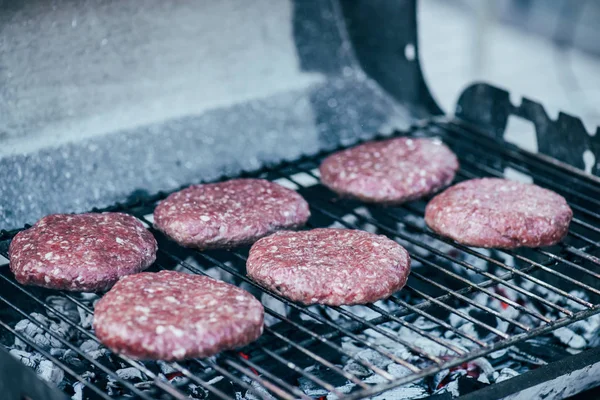Messa a fuoco selettiva di cotolette di hamburger fresco crudo grigliate sulla griglia bbq — Foto stock