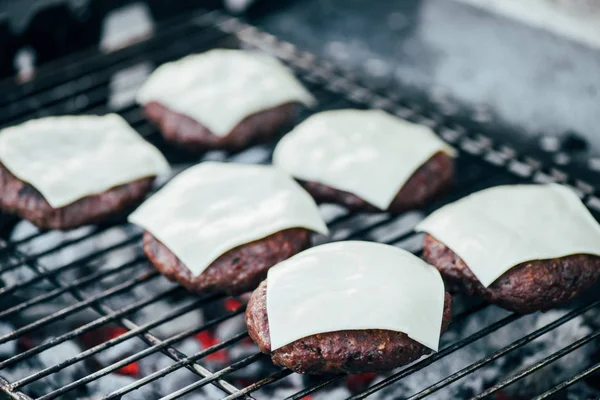 Selective focus of grilled fresh burger cutlets with cheese on bbq grid — Stock Photo