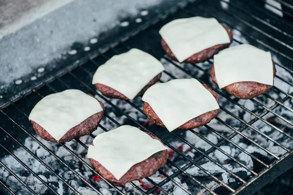 Foco seletivo de deliciosas costeletas de hambúrguer frescas com queijo grelhando na grade bbq — Fotografia de Stock