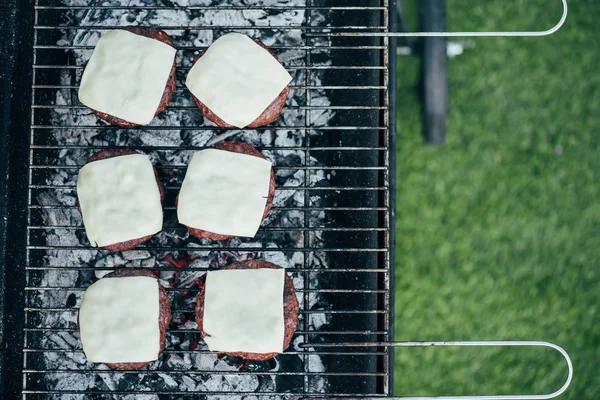Vue du dessus de délicieux escalopes de hamburger frais avec grillades au fromage sur grille de barbecue — Photo de stock