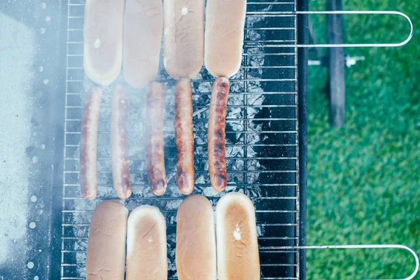 Вид на вкусные хот-доги на гриле барбекю класса на зеленом фоне травы — стоковое фото