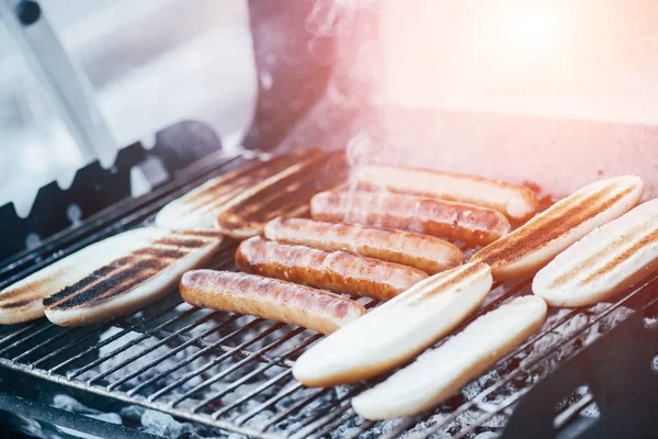 Délicieux hot-dogs griller avec de la fumée sur barbecue grill grade — Photo de stock