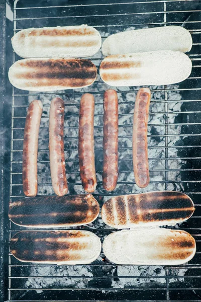 Vista superior de sabrosos perros calientes asar a la parrilla con humo en la parrilla de barbacoa grado - foto de stock