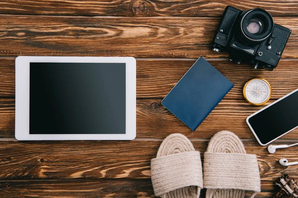 Vue de dessus des appareils numériques, caméra de film rétro, passeport et sandales en osier sur la surface en bois — Photo de stock