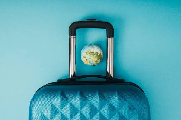 Vue du dessus du globe modèle et sac de voyage sur fond bleu — Photo de stock