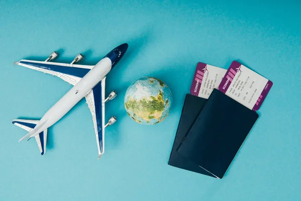 Vista dall'alto di modelli globo e aereo, passaporti con biglietti su sfondo blu — Foto stock