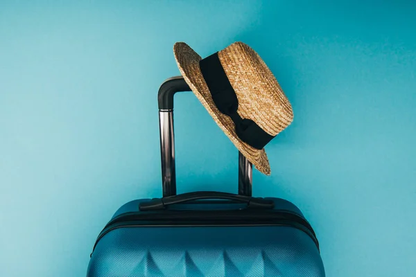 Vista superior del sombrero de paja y la bolsa de viaje sobre fondo azul - foto de stock