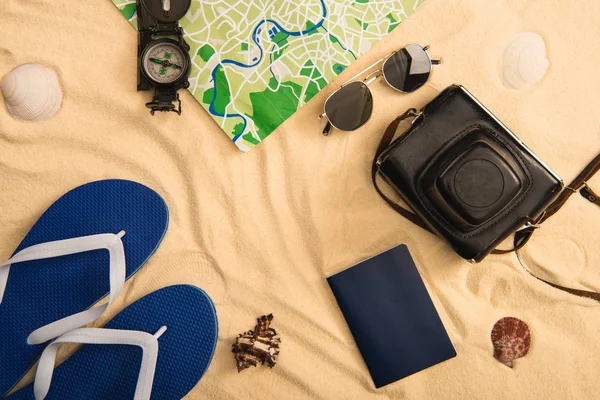 Vista dall'alto accessori estivi e mappa con bussola su sabbia con conchiglie — Foto stock