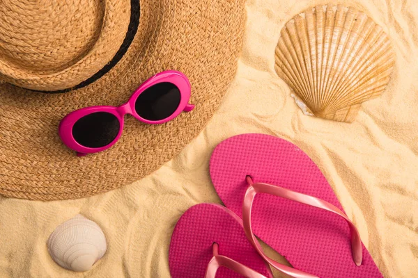 Top view of summer accessories and seashells on sand — Stock Photo