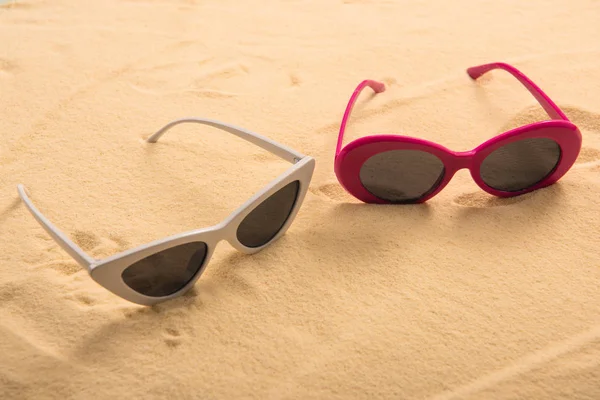 Pink and white sunglasses on golden clear sand — Stock Photo