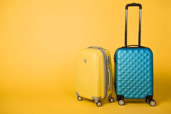 Bolsas de viaje de color amarillo brillante y azul sobre fondo amarillo - foto de stock