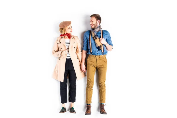 Elegante pareja tomados de la mano y sonriendo el uno al otro sobre fondo blanco - foto de stock