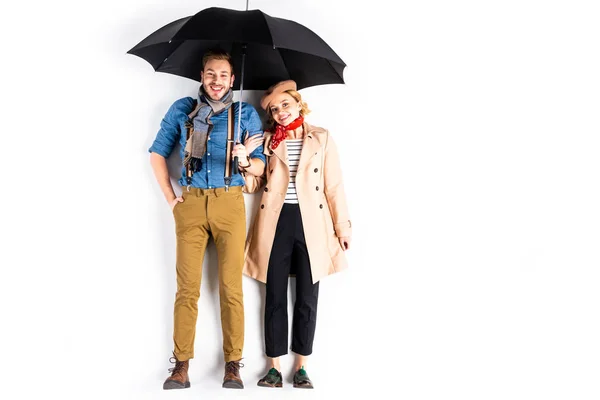 Pareja romántica de pie bajo el paraguas y sonriendo sobre fondo blanco - foto de stock