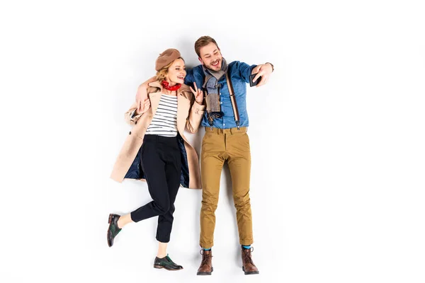 Stylish woman showing peace sign while taking selfie with boyfriend on white background — Stock Photo