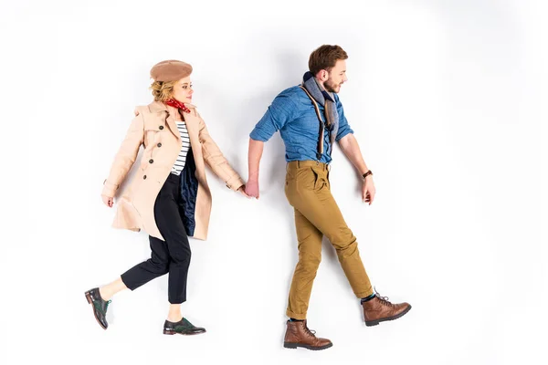 Elegant couple holding hands while walking on white background — Stock Photo