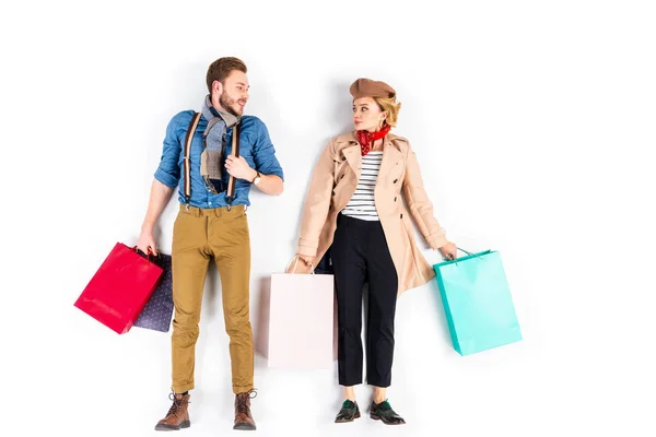 Funny couple with shopping bags looking at each other on white background — Stock Photo