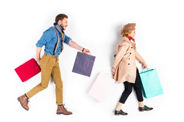 Pareja bien vestida con bolsas de compras caminando sobre fondo blanco - foto de stock