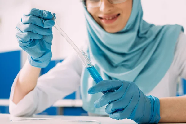 Vista recortada de la mujer musulmana científica sosteniendo tubo de ensayo y pipeta en el laboratorio - foto de stock