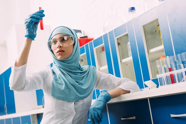 Femelle musulmane scientifique dans lunettes tenant éprouvette avec liquide rouge en laboratoire — Photo de stock