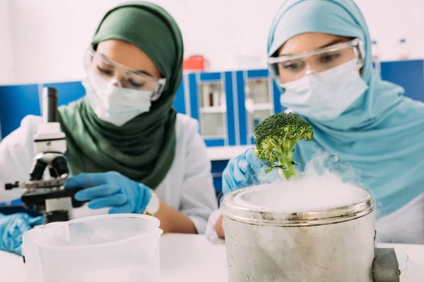 Cientistas muçulmanas fêmeas experimentando brócolis e gelo seco em laboratório químico — Fotografia de Stock