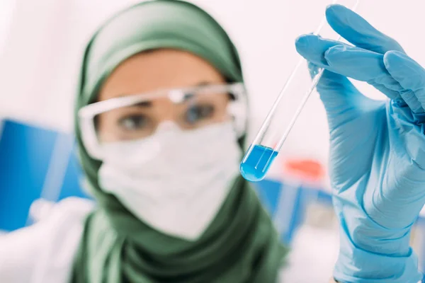 Mujer musulmana científica sosteniendo tubo de ensayo en laboratorio - foto de stock