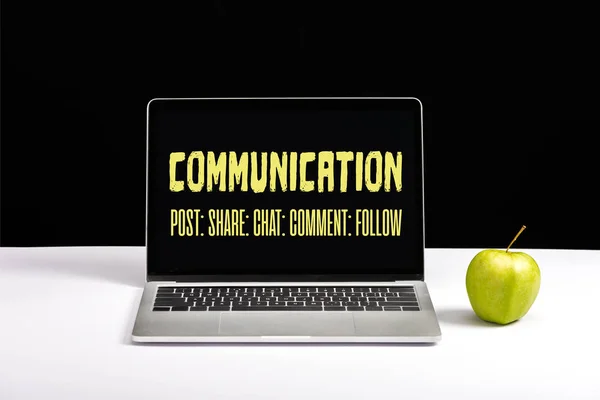 Свіже зелене яблуко і ноутбук на столі з комунікаційним написом на екрані ізольовані на чорному — стокове фото