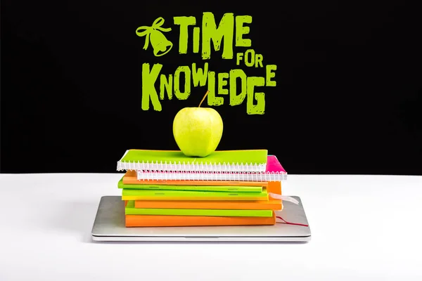 Laptop chiuso, mucchio di quaderni con mela verde in cima con tempo per la conoscenza lettering su nero — Foto stock