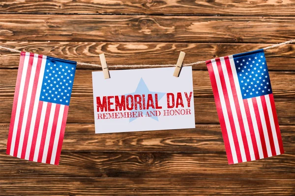 Card with memorial day lettering hanging on string with pins and american flags on wooden background — Stock Photo