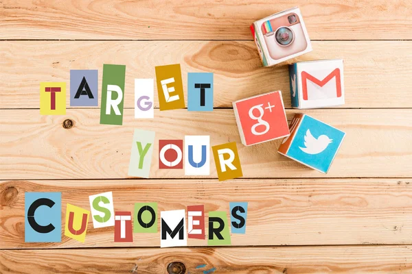 Top view of cubes with google plus, gmail, instagram and twitter logo on wooden table with target your customers lettering — Stock Photo