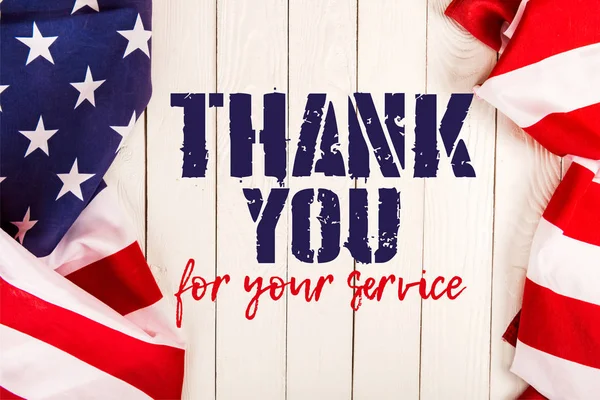 Draufsicht auf amerikanische Flaggen und Danke für Ihren Service-Schriftzug auf weißer Holzoberfläche — Stockfoto