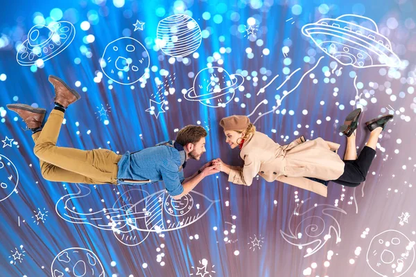 Elegante pareja tomados de la mano y volando juntos con la ilustración del espacio y destellos en el fondo - foto de stock