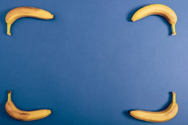 Top view of ripe and yellow bananas on blue background with copy space — Stock Photo