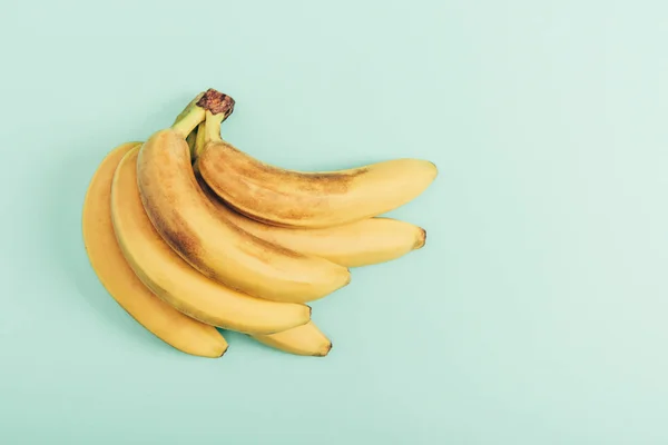 Вид зверху на стиглий букет яскравих бананів на бірюзовому фоні — стокове фото