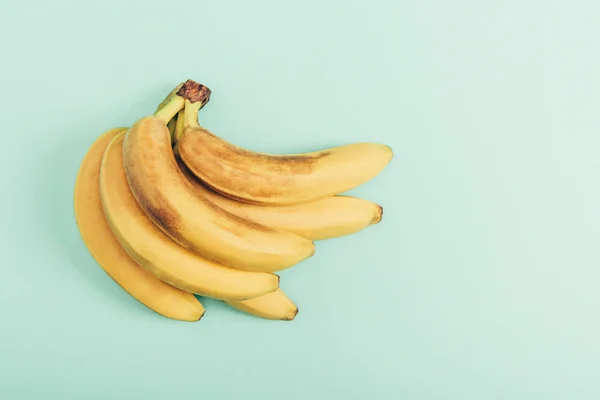 Vue du dessus du bouquet mûr de bananes vives sur fond turquoise — Photo de stock