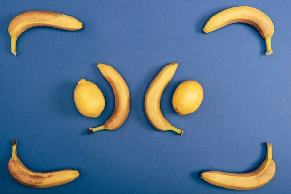 Draufsicht auf saftige und frische Zitronen mit gelben Bananen auf blauem Hintergrund — Stockfoto